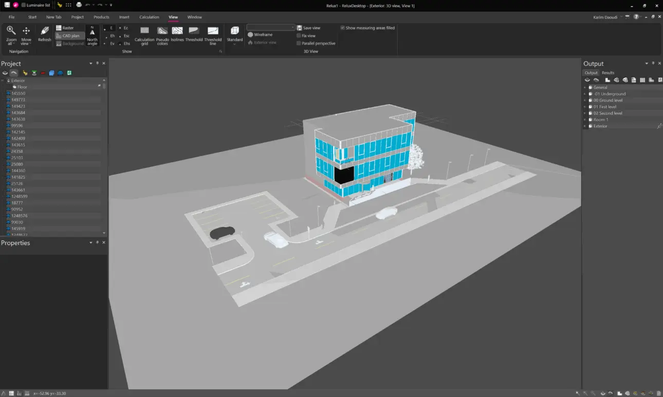 Vollständige Programmansicht der 3D-Arbeitsfläche in ReluxDesktop mit dem importierten Modell eines mehrstöckigen Bürogebäudes samt Parkplatzflächen, Straßenverlauf und Gehwegen unter einer simulierten Tageslicht-Hintergrundszene.